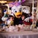 Daisy Duck hugging 2 Guests while they dine with their family at Navigator’s Club on the Disney Adventure cruise ship